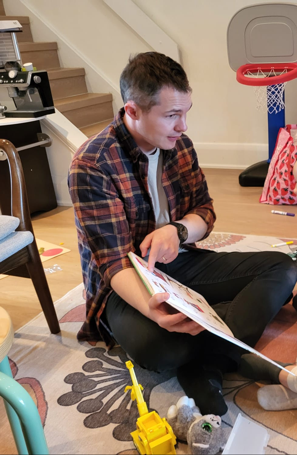 Man reading a book to two children in a home setting